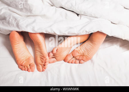 Morchie di un uomo e di una donna che dorme nel letto con lenzuola bianche di close-up Foto Stock