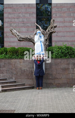 Una donna che prega davanti alla statua della santa Madre Teresa nella parte anteriore della Cattedrale di San Paolo a Tirana, Albania Foto Stock