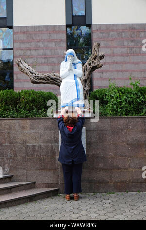 Una donna che prega davanti alla statua della santa Madre Teresa nella parte anteriore della Cattedrale di San Paolo a Tirana, Albania Foto Stock