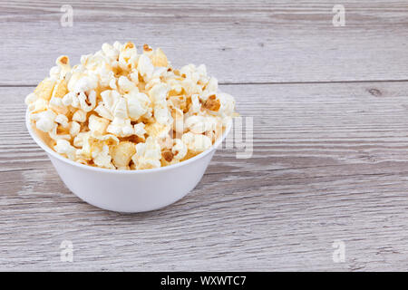 Il Popcorn in un recipiente su un sfondo di legno Foto Stock