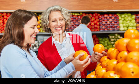 Due donne in quanto i clienti durante lo shopping per le arance nella sezione vegetale Foto Stock