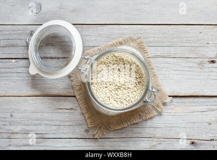 Grano di sorgo in un vasetto di vetro su sfondo di legno Foto Stock