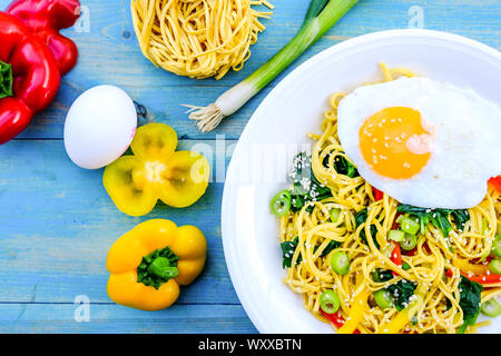 A base di noodle all'uovo e pepe insalata con peperoni rossi e gialli, spinaci, cipolline, i semi di sesamo e un uovo fritto Foto Stock