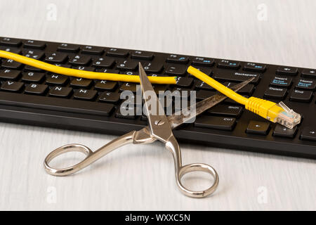 Forbici e tagliate il cavo di rete al di sopra della tastiera del computer. Scollegamento radicale internet Foto Stock