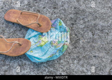 Indossato hippy flipflops & globo sgonfiato sulla superficie di calcestruzzo. Metafora terra piatta, flat earthers, teorie cospirative, piano terra prove, pseudoscience Foto Stock