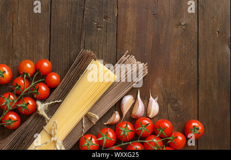 Tre tipi di spaghetti, pomodoro e aglio su legno Foto Stock