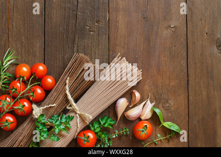 Tre tipi di spaghetti, i pomodori e le erbe su legno Foto Stock