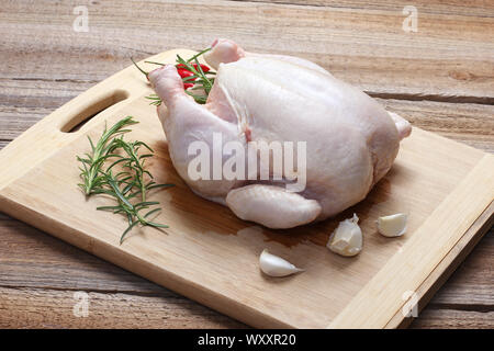Il pollo intero con la pelle sul tagliere Foto Stock