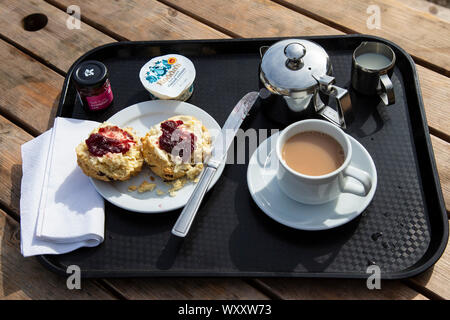 Un molto crema inglese tè serviti con un cornetto, clotted cream e fragola o confettura di lamponi con lunghe controversie in piedi sopra la marmellata o la crema prima Foto Stock