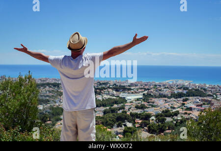 Giovane maschio traveler stand con le braccia spalancate, gode di una splendida vista di fronte a lui, il concetto di libertà Foto Stock