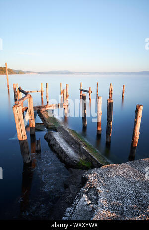 Un vecchio molo in legno sommerse dalle acque del lago di Bolsena, all'alba, in Marta Foto Stock