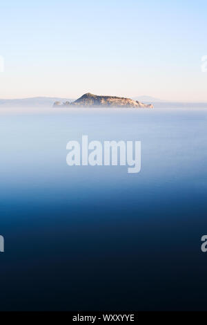 La Martana isola nel Lago di Bolsena, con una lunga esposizione al mattino all'alba con la nebbia Foto Stock