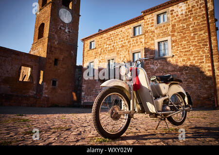 Un bianco vintage Aermacchi moto, al tramonto, in un italiano tradizionale villaggio storico, nella città fantasma di Celleno Foto Stock