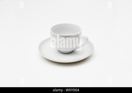 Un elegante e antica ceramica bianca tazza da caffè con piattino isolata su uno sfondo uniforme Foto Stock