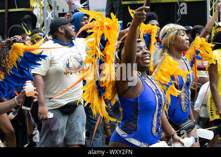 Tanzend zu lauter Musik laufen Teilnehmer der West Indian Day Parade di New York City Un den Zuschauern vorbei und animieren diese. Foto Stock