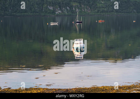 Barche in Lochcarron con drammatica mattina presto luce con uno sfondo scuro creato dalla collina riflessa attraverso il loch. Foto Stock