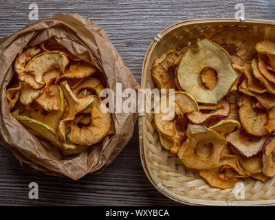 In casa sun-organico essiccato di fette di mela croccante chip Apple, su sfondo di legno e fresh apple. Spazio di copia Foto Stock