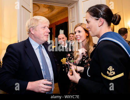 Il primo ministro Boris Johnson parla ad un ospite che ospita un ricevimento militare, con il suo partner Carrie Symonds (centro), al 10 Downing Street, Londra. Foto Stock