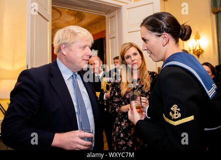 Il primo ministro Boris Johnson parla ad un ospite che ospita un ricevimento militare, con il suo partner Carrie Symonds (centro), al 10 Downing Street, Londra. Foto Stock