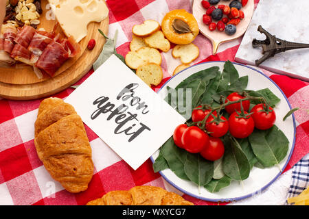 Elegante pic nic sul prato verde. Cornetti freschi e una teiera con il tè su un copriletto vicino a una femmina di vimini hat. Instagram contenuto. Foto Stock