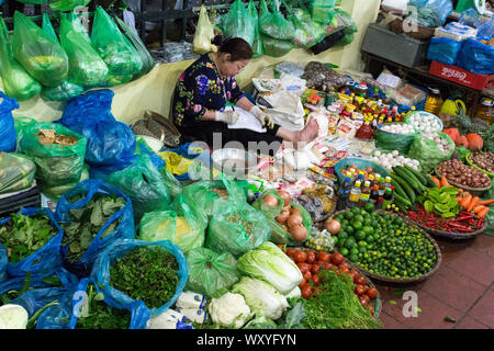 Hanoi, Vietnam - Dicembre 26, 2016: Womand la vendita di frutta e verdura in un mercato di strada di Hoan Kiem, il quartiere vecchio di Hanoi Foto Stock