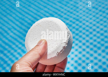 Mano azienda pellet di cloro con piscina gonfiabile su sfondo Foto Stock