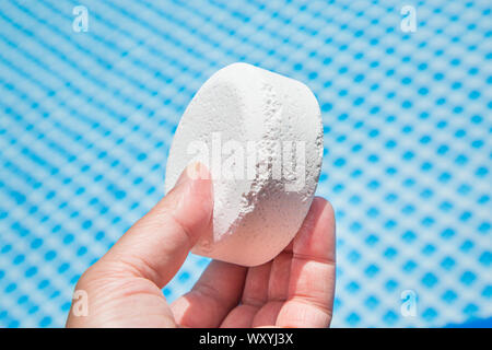 Mano azienda pellet di cloro con piscina gonfiabile su sfondo Foto Stock