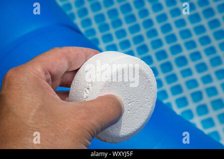 Mano azienda pellet di cloro con piscina gonfiabile su sfondo Foto Stock