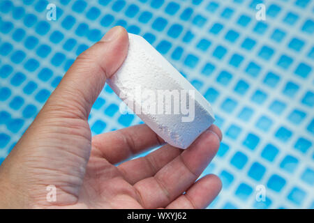 Mano azienda pellet di cloro con piscina gonfiabile su sfondo Foto Stock