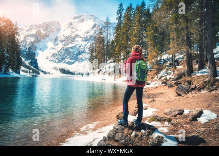 Donna con zaino sulla pietra vicino al lago con acque azzurre Foto Stock