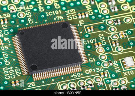 Close-up di semiconduttori integrati sul microchip scheda di circuito. A montaggio superficiale e tecnologia dei componenti elettronici. Hardware del computer su una texture verde. Foto Stock