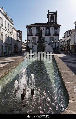 Primo piano della fontana e piscina riflettente di fronte a Ponta Delgada City Hall e la statua di San Michele Arcangelo in São Sebastião parrocchia Foto Stock