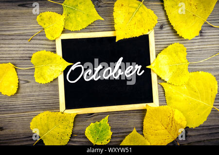 Colorato in giallo le foglie di autunno sul tavolo di legno e lavagna scritto ottobre testo, caduta stagione concept Foto Stock