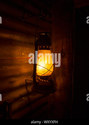 Retrò vecchia lanterna di kerosene con un ferro corrugato parete e sfondo scuro dello sfondo Foto Stock