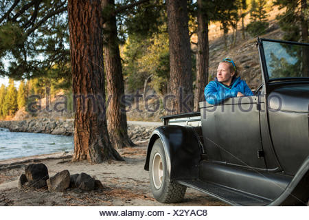 Donna seduta nel rinnovato carrello guardando il tramonto sul Lago Payette, McCall, Idaho, Stati Uniti d'America