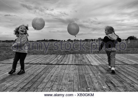 Due ragazze che giocano all'aperto con palloncini Foto Stock
