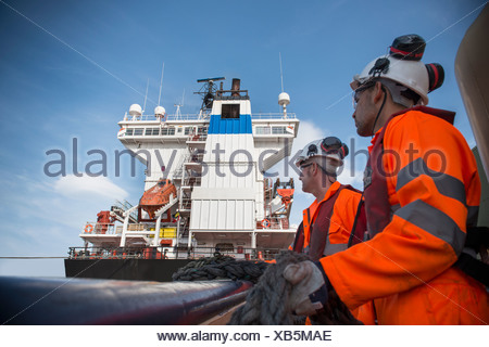 Lavoratori sul rimorchiatore tirando in corda Foto Stock