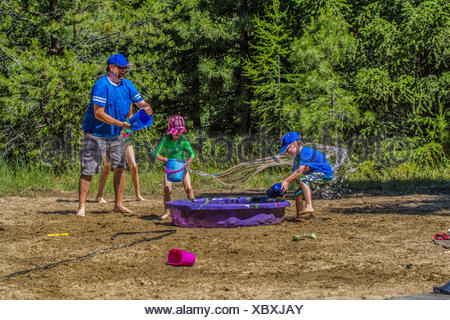 Per adulti e bambini in acqua playfull lotta , su una calda e soleggiata giornata estiva. Cranbrook, British Columbia, Canada.