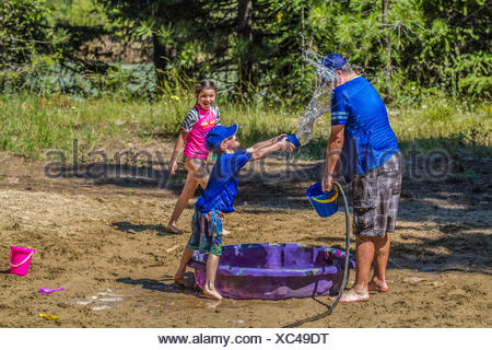 Per adulti e bambini in acqua playfull lotta , su una calda e soleggiata giornata estiva. Cranbrook, British Columbia, Canada.