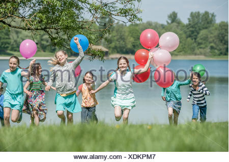 I bambini in esecuzione nel parco con palloncini, Monaco di Baviera, Germania Foto Stock