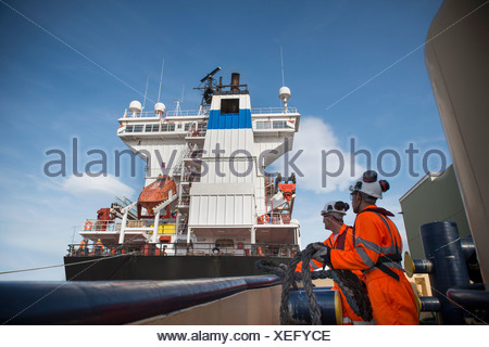 Lavoratori sul rimorchiatore tirando in corda Foto Stock